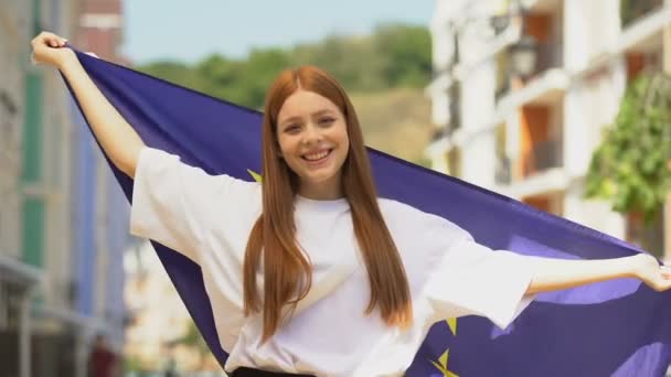Jovem alegre do sexo feminino acenando bandeira da União Europeia e enviando beijo de ar na câmera — Vídeo de Stock