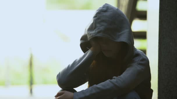 Melancholic teen female in hoodie touching face with palm, suffering depression — Stock Video