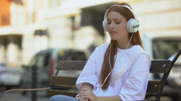 Συναισθηματική θλιμμένη έφηβη σε ακουστικά ακούγοντας λυρικό τραγούδι υπαίθρια εφαρμογή μουσικής — Αρχείο Βίντεο