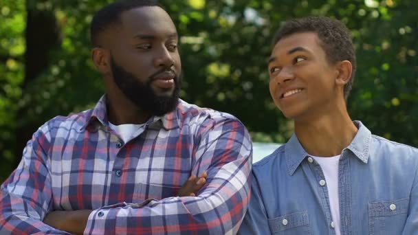 Афро-американский отец и сын смотрят в камеру и улыбаются, счастливая семья — стоковое видео