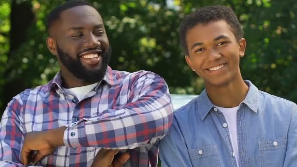 Souriant papa afro-américain étreignant son fils et regardant vers la caméra, ensemble — Video