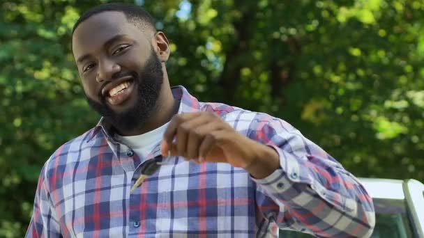 Feliz hombre afro-americano sonriente mostrando las llaves del coche a la cámara, nueva compra de automóviles — Vídeo de stock