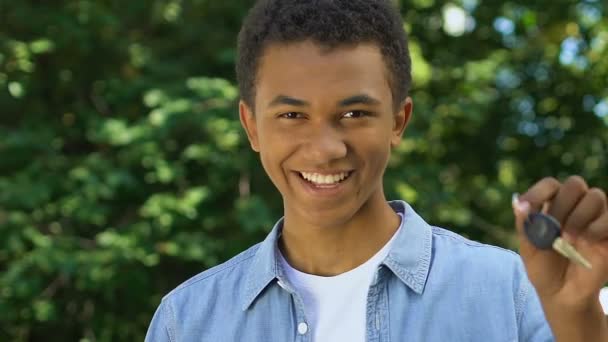 Boldog fekete tinédzser fiú mutatja auto kulcsok kamera, szerzés jogosítvány — Stock videók