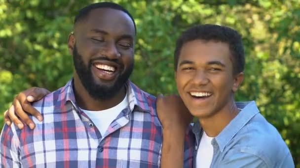 Alegre afro-americano adolescente abrazando sonriente padre, feliz retrato familiar — Vídeo de stock