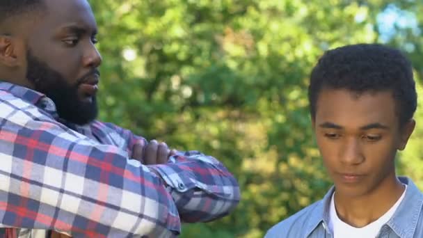 Afro-american father scolding son, teenage boy feeling guilty, young age mistake — Stock Video