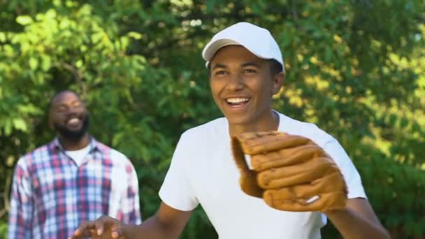 Orgulloso padre afroamericano animando a su hijo adolescente a jugar béisbol, juntos — Vídeo de stock