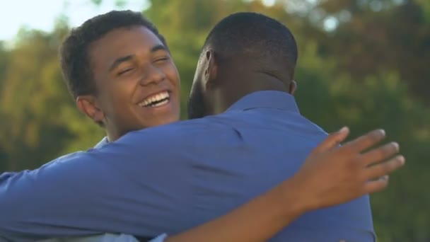 Sonriente hombre afroamericano abrazando a hijo adolescente, sintiéndose feliz y orgulloso, confianza — Vídeo de stock