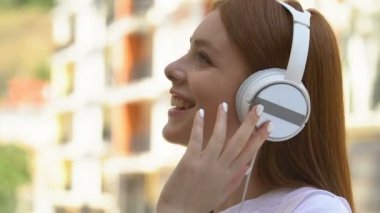 Beyaz kulaklıklı mutlu genç müzik dinliyor melodi seslerinin tadını çıkarıyor