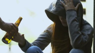 Üzgün genç kadın elinden bira şişesi alıyor, kötü sokak etkisi bağımlılığı