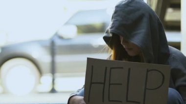 Erkek, elinde yardım işareti tutan yoksul bir kadını destekliyor. Gönüllü bağış yapıyor.