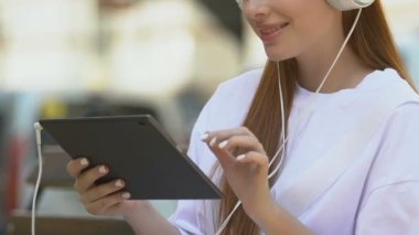 Gülümseyen kolej öğrencisi kulaklıkla tablet, online alışveriş uygulaması, alet kullanıyor.