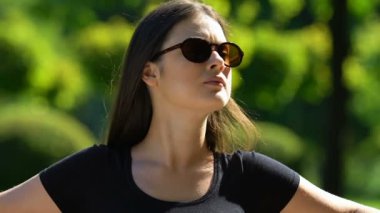 Milenyum kadını şık güneş gözlükleriyle parkta bankta dinleniyor.