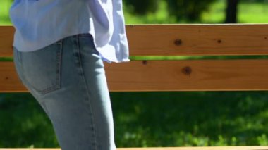 Zayıf bir kadın sırt ağrısı çekiyor, parkta bankta oturuyor, iltihap kapmış.