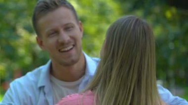 Gülümseyen erkek arkadaş kız arkadaşına şefkatle sarılıyor, uzun zamandır beklenen buluşma, randevu.