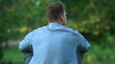 Yalnız adam dışarıda oturur, düşünür ve park eden insanları seyreder.