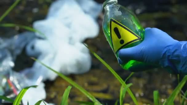 Mano en guante protector vertiendo líquido peligroso en el vertedero, contaminación de la tierra — Vídeo de stock