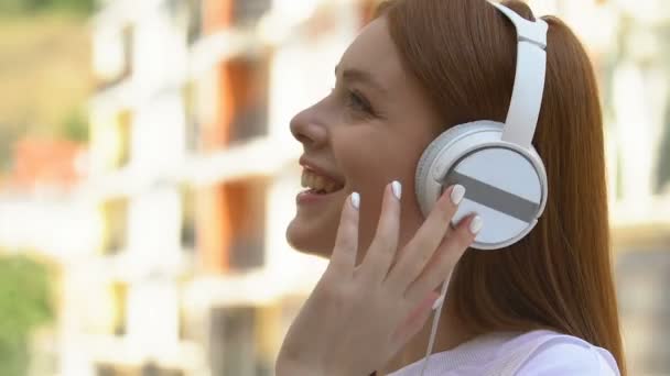 Glad tonåring i vita hörlurar lyssnar på musik njuter melodi ljud — Stockvideo