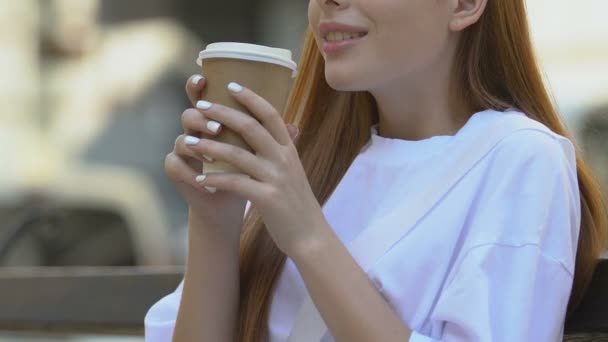 Счастливая молодая женщина пьет кофе на открытом воздухе наслаждаясь вкусом напитка, забрать — стоковое видео