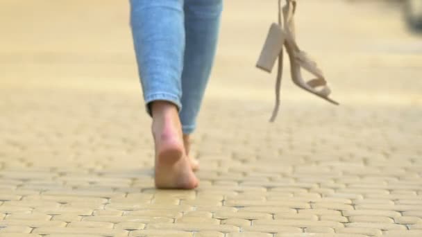 Безтурботна жінка, що ходить босоніж, тримає високі босоніжки на п'яті, свобода комфорту — стокове відео