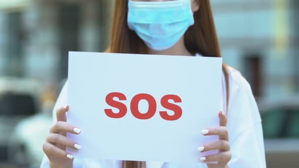 Mujer con máscara protectora sosteniendo signo SOS, desastre ecológico, contaminación urbana — Vídeos de Stock