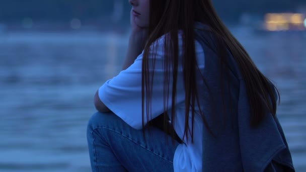 Несчастная женщина тысячелетия сидит речной берег города сумерки, проблемы полового созревания — стоковое видео
