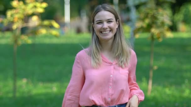 Schöne junge Frau lächelt aufrichtig in die Kamera im Park, Ruhe und Wellness — Stockvideo