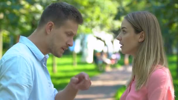 Casal jovem brigando ao ar livre, homem e mulher tendo reivindicações uns aos outros — Vídeo de Stock