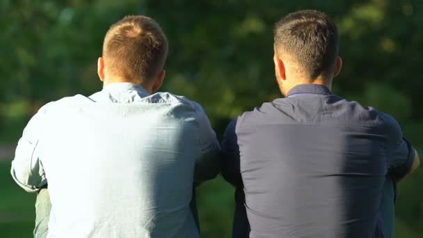 Zwei beste Freunde sitzen draußen und diskutieren über Lebensprobleme, Freundschaft, Rückansicht — Stockvideo
