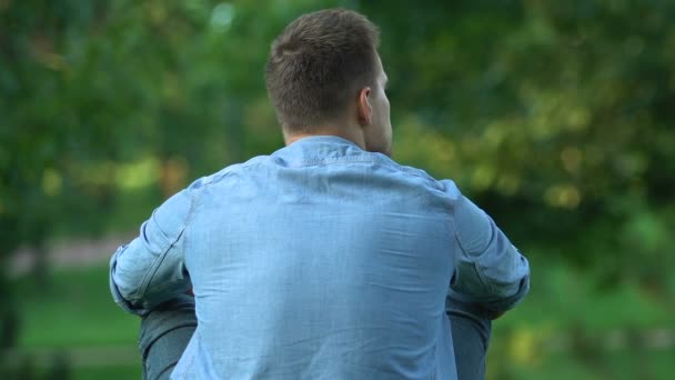 Solitario chico sentado al aire libre pensando y viendo a la gente caminar parque, vista trasera — Vídeos de Stock