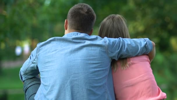 Par förälskade sitter utomhus, kille ömt omfamna sin flicka, back-view — Stockvideo