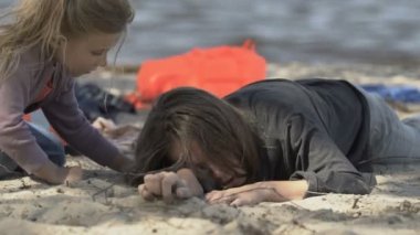 Okyanus kıyısında acıdan ağlayan annesine sarılan bir kız, uçak kazası kurbanları.
