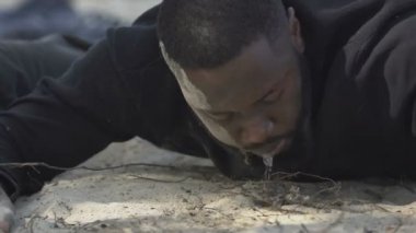 Afro-Amerikalı adam kendine geliyor, su tükürüyor, fırtına kurbanı.