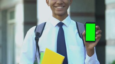 Cep telefonu gösteren gülümseyen bir öğrenci, çevrimiçi okula kayıt başvuruları