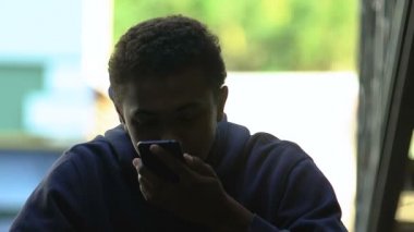 Afro-Amerikalı genç erkek sigara içiyor ve kızgın bir şekilde telefonla konuşuyor.