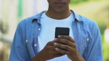 Afro-Amerikalı genç çocuk dışarıda akıllı telefonla konuşuyor, sevgilisinden mesaj var.