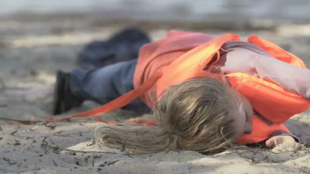 Kleines Mädchen mit Trauma zieht Schwimmweste aus und liegt nach Schiffbruch am Strand — Stockvideo