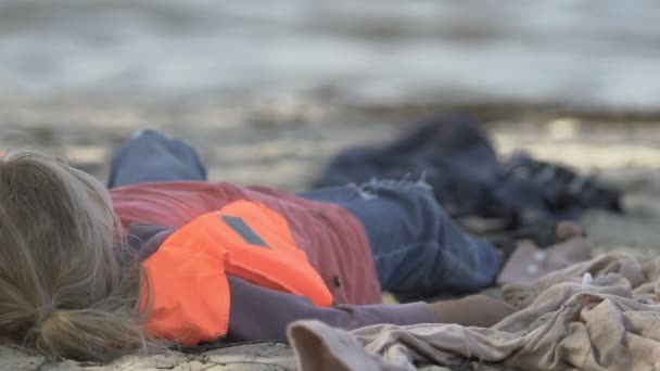 Niña en chaleco salvavidas escupiendo agua en la costa del mar, naufragio sobrevivió víctima — Vídeos de Stock