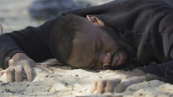 Afro-amerikai férfi menekült, szomjas, homokon fekszik, elveszett a sivatagban. — Stock videók