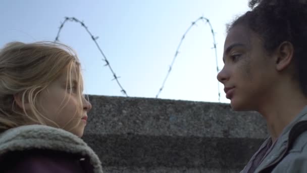 Multiraciale kinderen knuffelen achter de muur met kapper draad, afscheid in weeshuis — Stockvideo