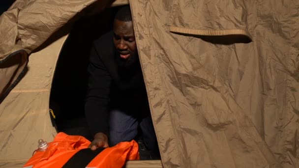 African-American man in tent hugging life vest and crying after family death — Stock Video