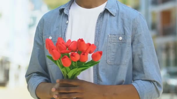 Garçon inquiet tenant des fleurs, regardant dehors pour la petite amie en retard pour la date, rupture — Video