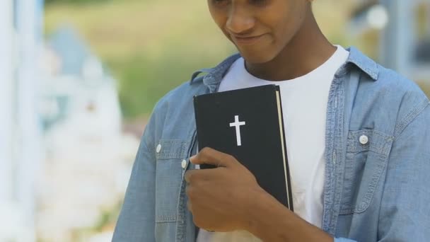 Afrikansk-amerikan pojke omfamnar Bibeln, religiös kallelse till präster, präst — Stockvideo