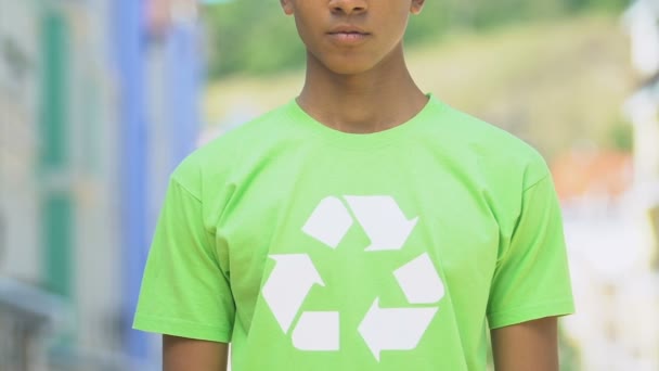 Niño serio en camisa con signo de reciclaje que promueve productos reutilizables, conciencia — Vídeo de stock