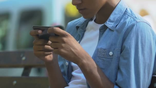 Závislý afroameričan teenager nervózně přehrává videohru na smartphonu — Stock video