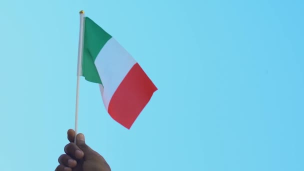 Hand eines schwarzen Mannes mit italienischer Flagge vor himmelblauem Hintergrund, Patriotismus — Stockvideo
