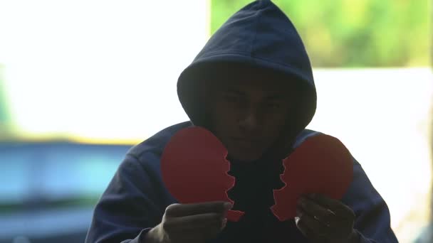 Depressed male teenager putting together two pieces of broken heart, break-up — Stock Video