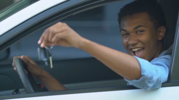 Heureux noir mâle adolescent sur pilote place montrant voiture clés, première automobile — Video