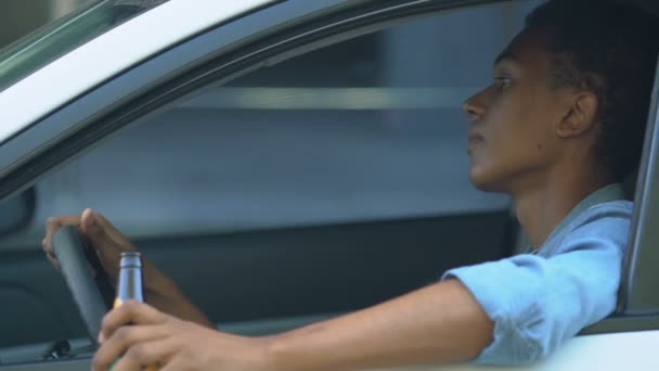 Irresponsible black teen boy drinking beer on driver place, risk of accident — Stock Video