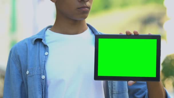 Ciddi bir Afro-Amerikan genci yeşil ekranlı tableti işaret ediyor. — Stok video