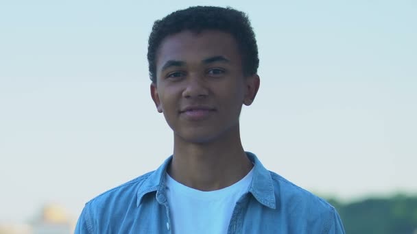 Happy African-American teenager boy smiling at camera outdoors, positivity — ストック動画